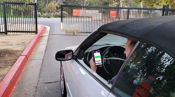 public storage employee in gray car uses new public storage app to remotely open gate